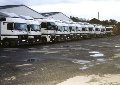 Rangée de camions garés à côté de grands entrepôts.