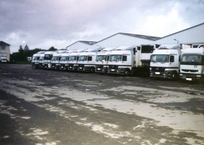 Une rangée de camions garés côte à côte dans une cour d'entrepôt.