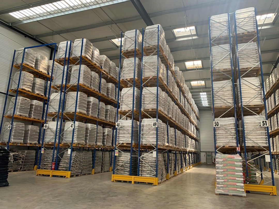 stockage De grands rayonnages d'entrepôt empilant des palettes de marchandises dans une installation de stockage spacieuse et bien éclairée.